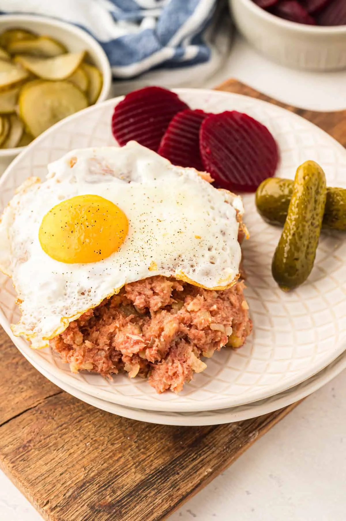 Labskaus auf weißem Teller mit Spiegelei, Rote Bete und sauren Gurken – ein klassisches norddeutsches Labskaus Rezept