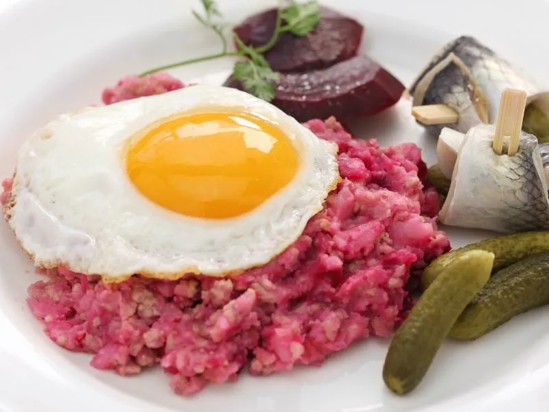 Labskaus-Brei mit Roter Bete und Corned Beef, fertig zum Anrichten mit Beilagen.