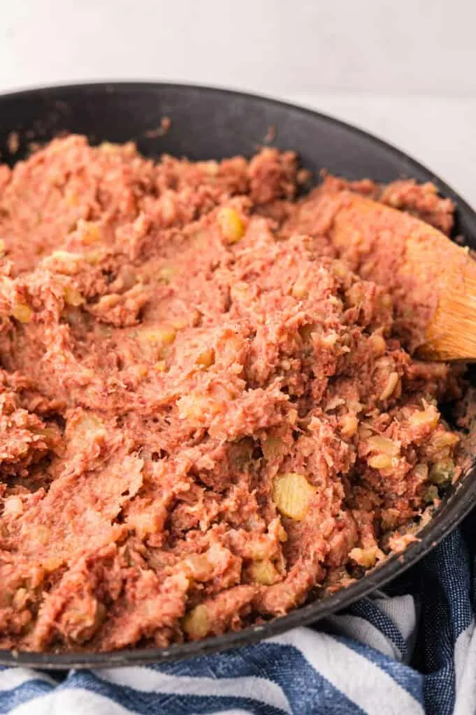 Labskaus in einer schwarzen Pfanne mit Holzlöffel, bereit zum Servieren