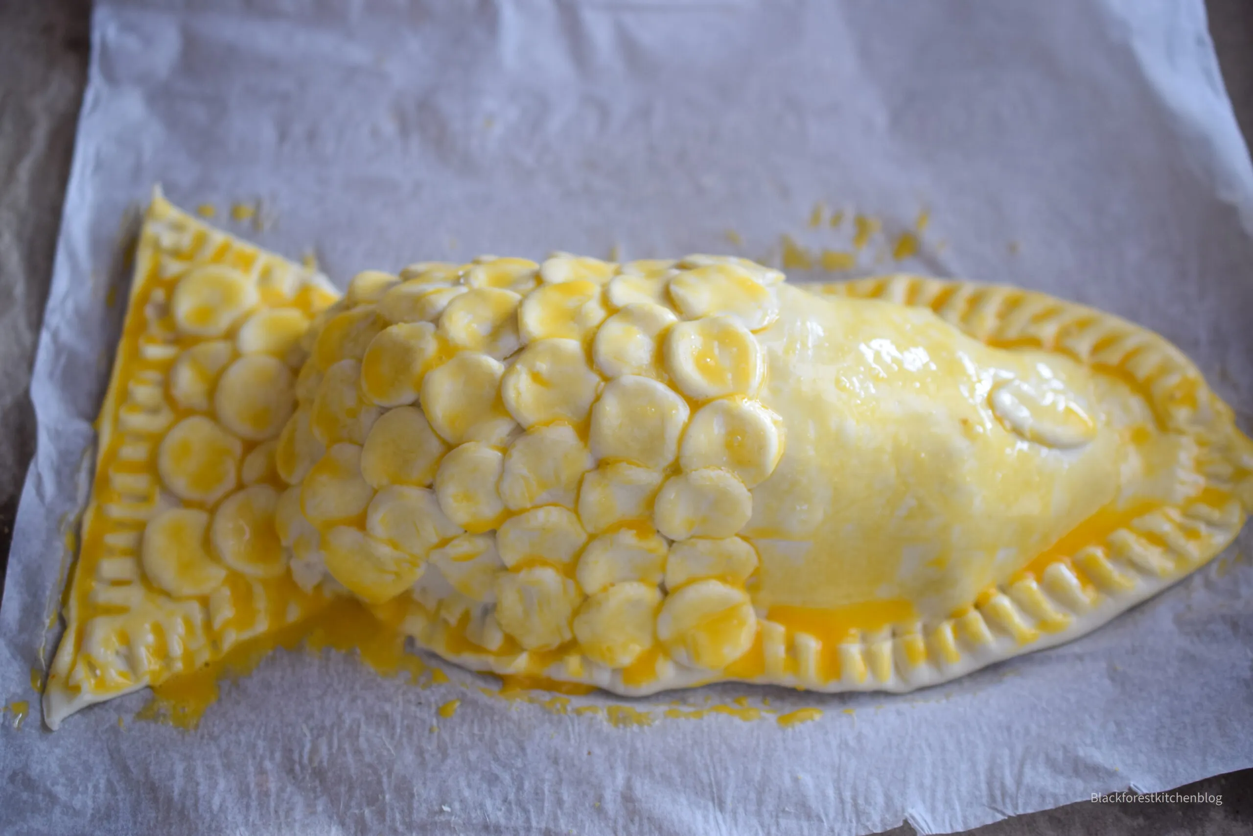 Lachsfilet mit Fenchel-Karotten-Cremefraiche-Füllung, umhüllt von Blätterteig, noch ungebacken, mit Fischschuppen-Verzierung