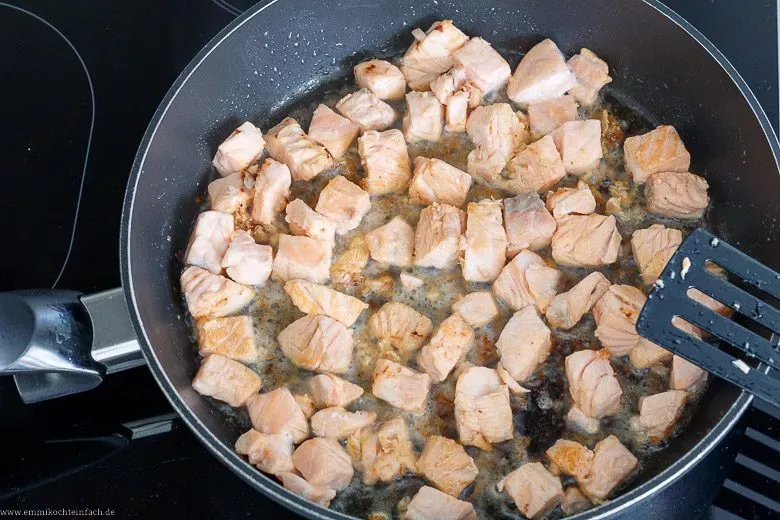 Lachswürfel werden in einer Pfanne angebraten, um Röstaromen zu entwickeln