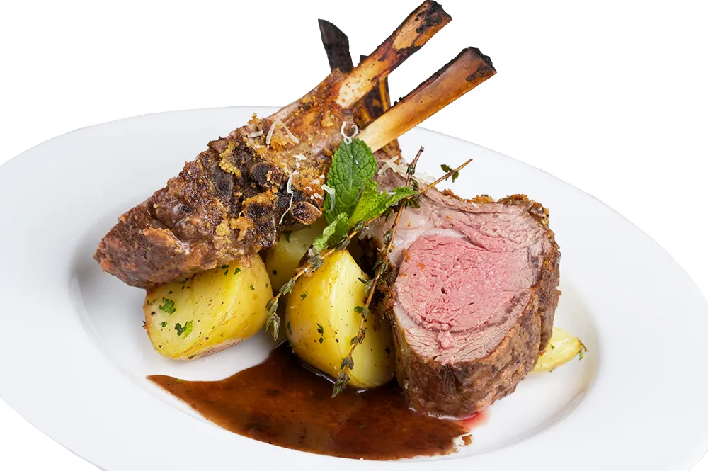 Lammkrone angerichtet auf einem Teller mit Sauce und Petersilienkartoffeln