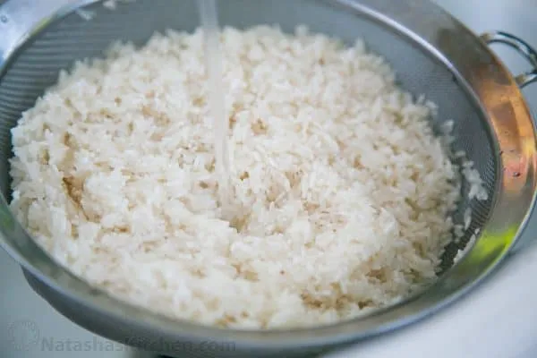 Langkornreis wird unter fließendem Wasser gründlich gespült, um überschüssige Stärke zu entfernen und einen lockeren Reis zu gewährleisten