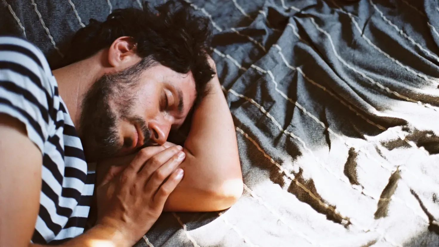 Mann erholt sich im Bett von einem Magen-Darm-Infekt und Bauchschmerzen