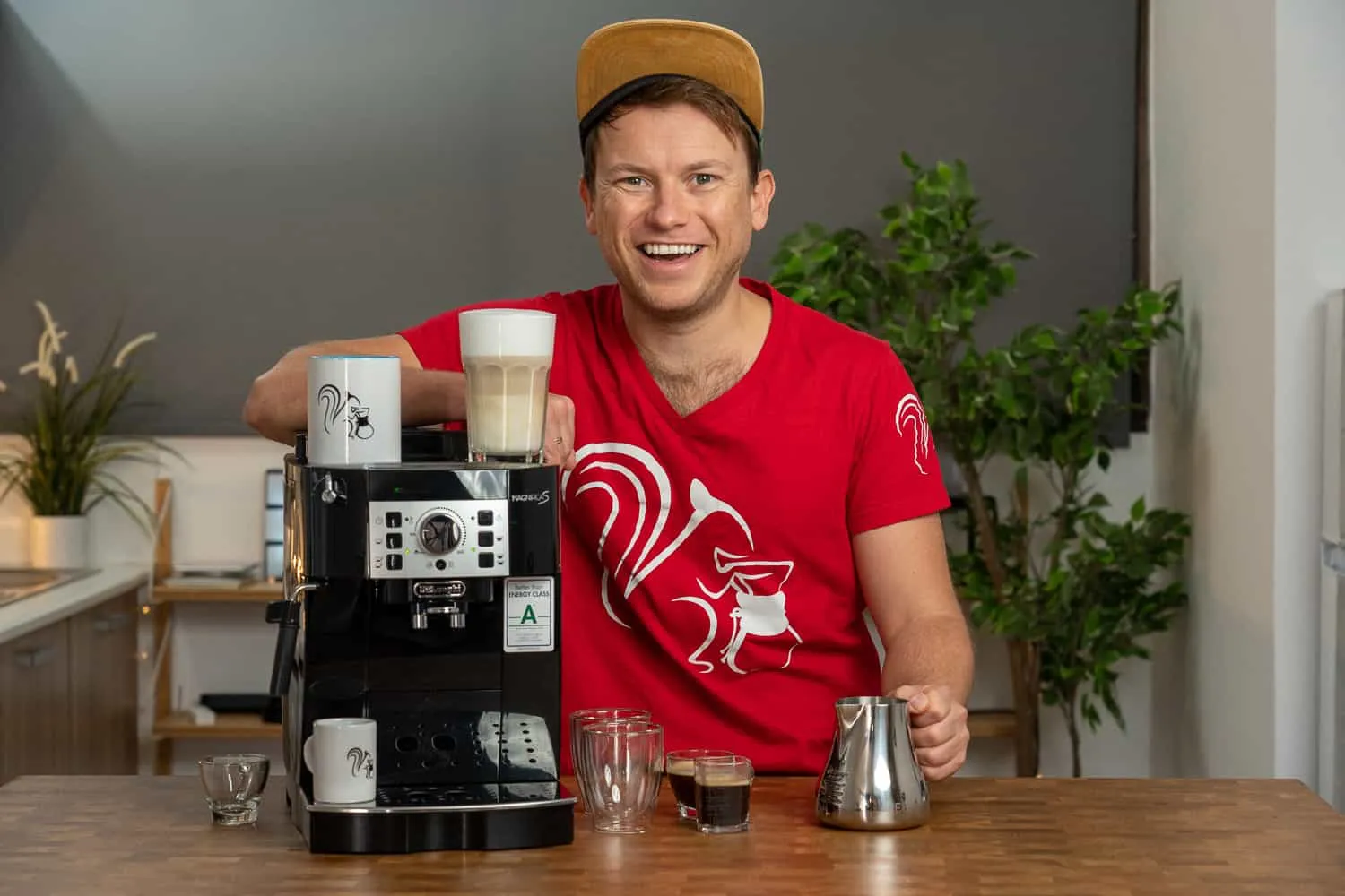 Mann lächelt mit DeLonghi Magnifica ECAM 22.110.B Kaffeevollautomat und fertigen Getränken