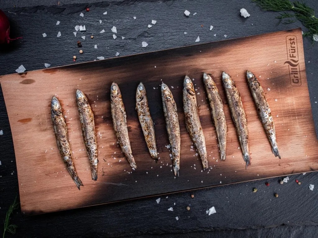 Marinierte Sardinen auf einem Räucherbrett garen schonend und nehmen köstliche Raucharomen an.