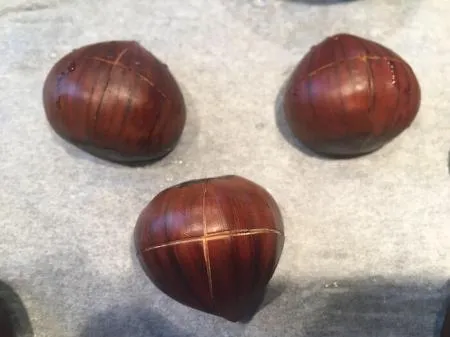 Maroni kreuzweise an der runden Seite eingeschnitten, bereit zum Braten