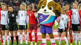 Maskottchen Maddli, ein Bernhardiner-Welpe, posiert mit Spielerinnen der deutschen und schweizerischen Frauen-Nationalmannschaft.