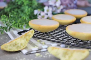 Mehrere leckere Amerikaner mit weißem Zitronenguss auf einem Teller, perfekt angerichtet und bereit für den Kaffeetisch. Ein traditionelles deutsches Gebäck, das Kindheitserinnerungen weckt.