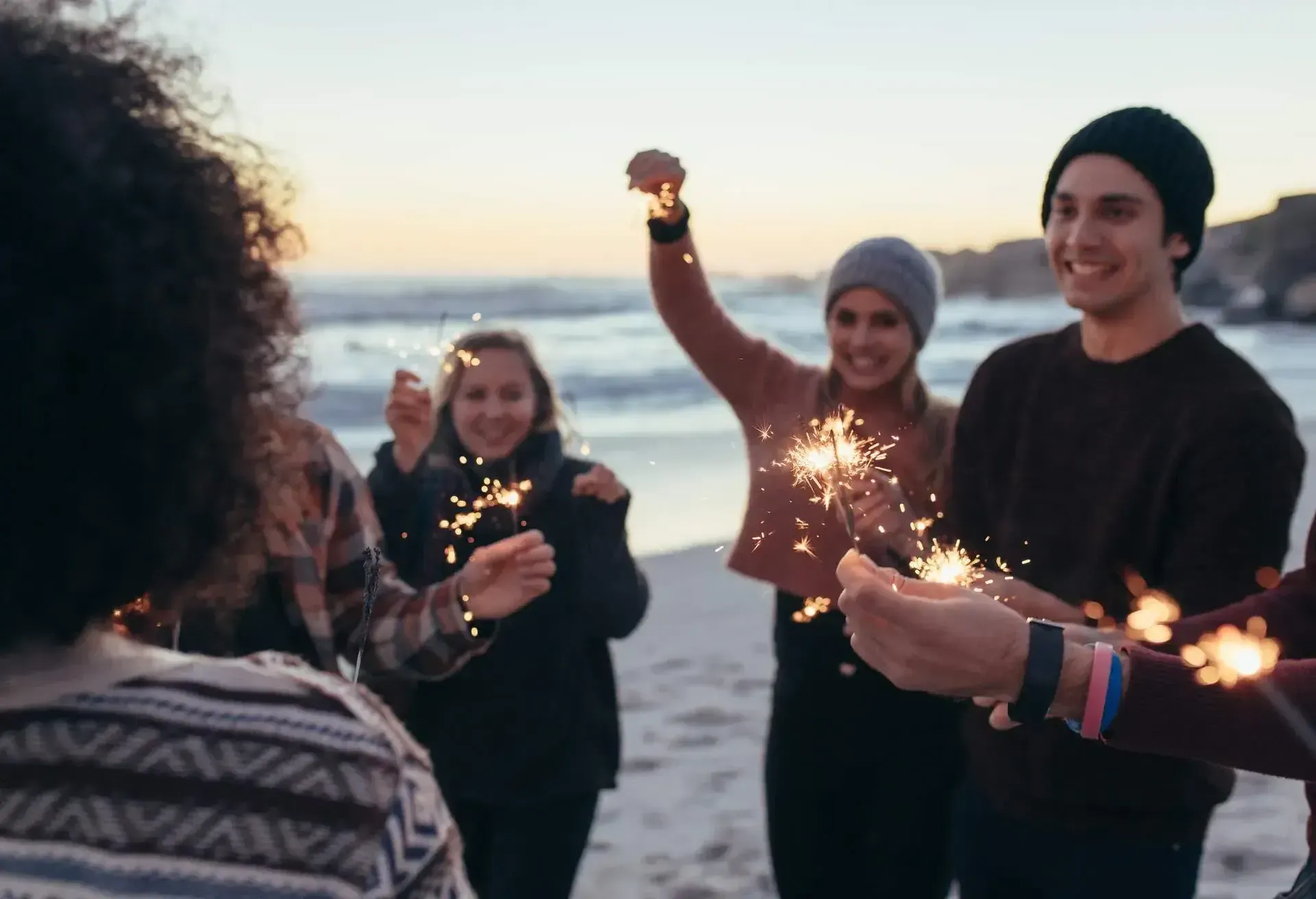 Menschen halten Wunderkerzen am Strand von Helgoland