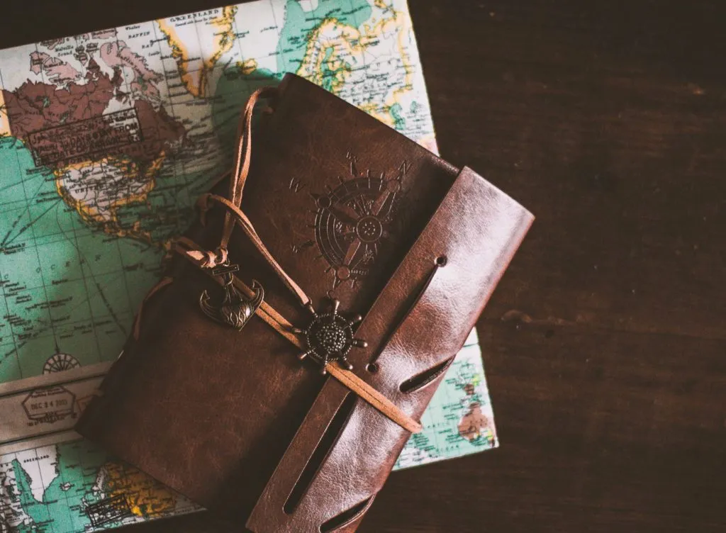 Menschen laufen über eine weite grüne Heidelandschaft mit Bäumen und einem blauen Himmel