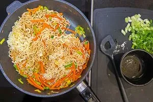 Mie-Nudeln werden in der Pfanne mit Soße und Gemüse vermengt – ein häufiger Anblick in deutschen Küchen