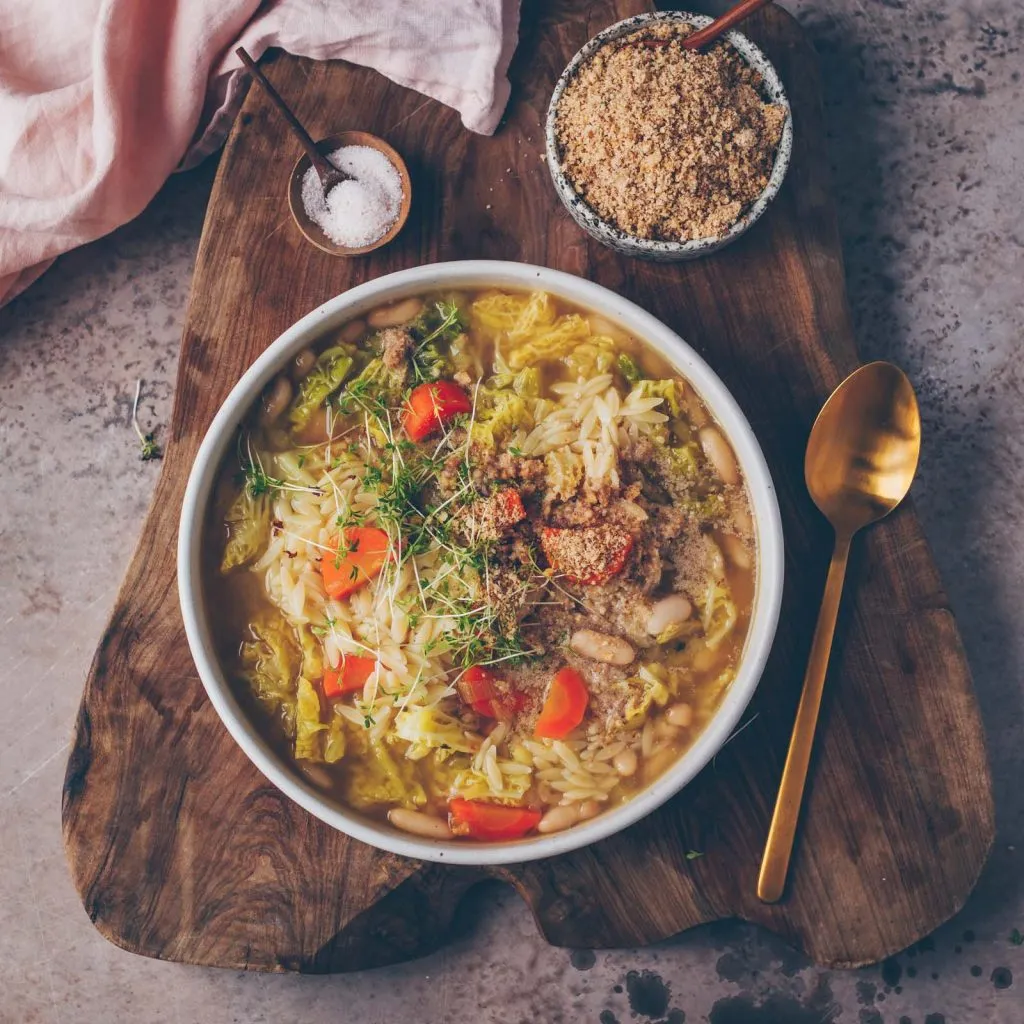 Minestrone Suppe mit Wirsing, weißen Bohnen und Risoni Nudeln in einer Schale serviert