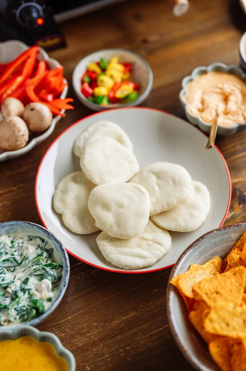 Mini-Pizza im Raclette-Pfännchen mit frischen Zutaten vor dem Überbacken
