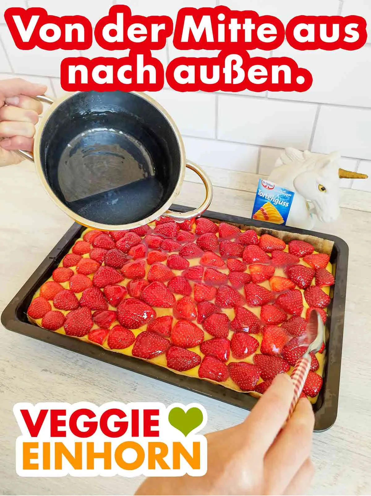 Mit einem Esslöffel wird der vegane Tortenguss von Dr. Oetker auf dem Kuchen verteilt.