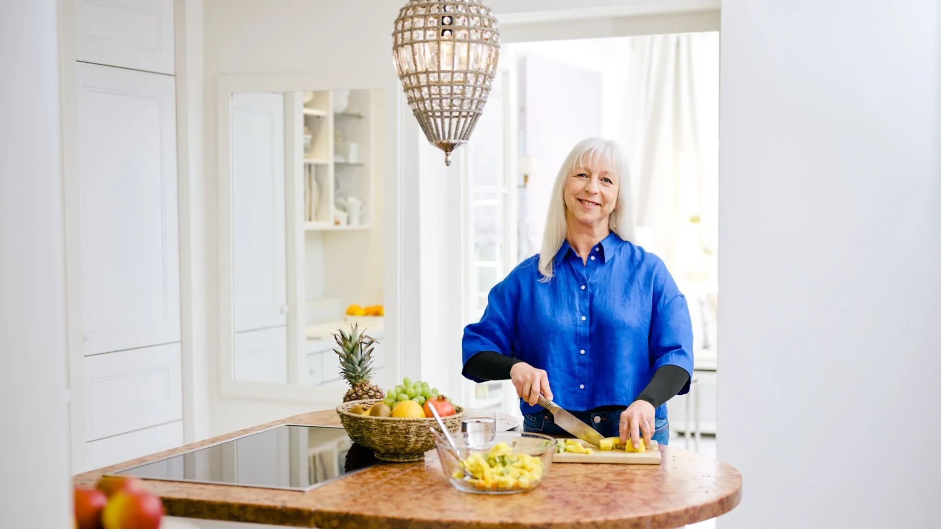 Model Ursula schneidet Obst als Teil einer mediterranen Ernährung.