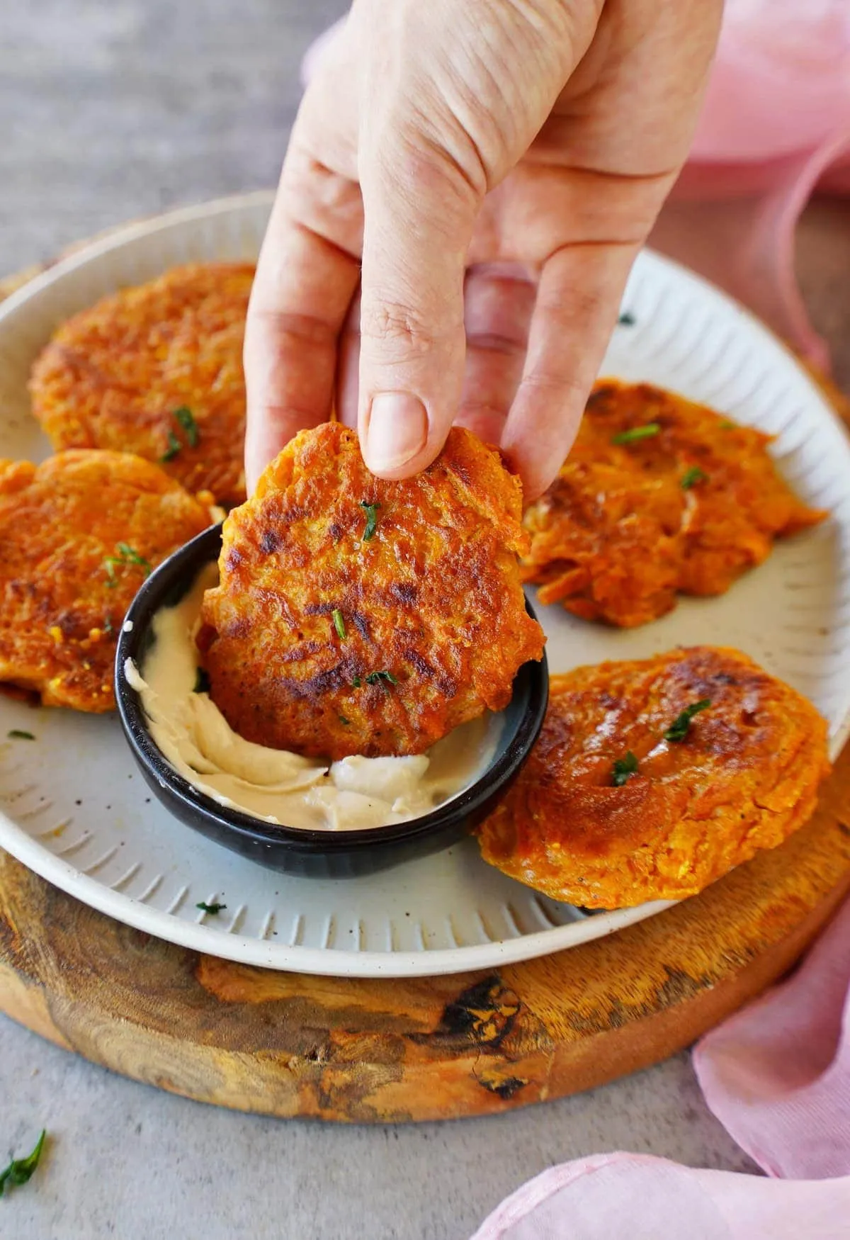 Möhren-Puffer wird mit der Hand in Soße getaucht