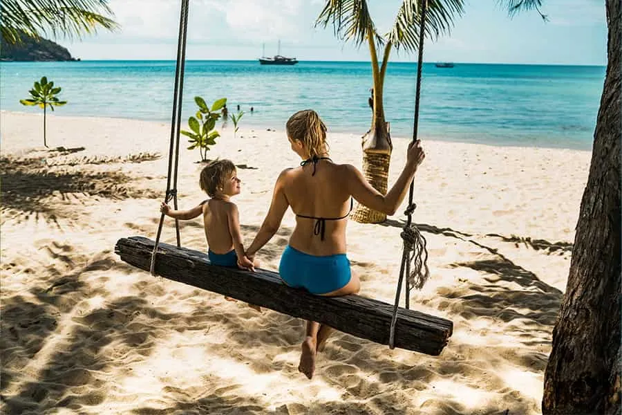 Mutter und Kind genießen entspannten Strandurlaub in einer Hängematte – ein Angebot Ihres sonnenklar.TV Reisebüro.