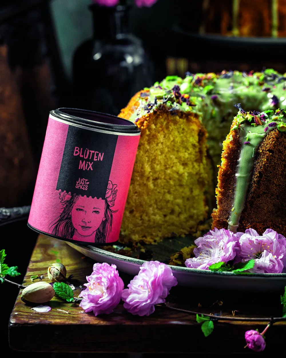 Nahaufnahme der frühlingshaften Dekoration eines Marzipan-Kuchens für Ostern, mit zarten Blüten auf der grünen Pistazienglasur