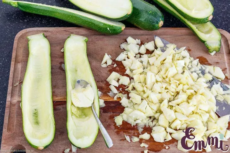 Nahaufnahme des Aushöhlens einer Zucchinihälfte mit einem Löffel für das Füllen mit Hackfleisch