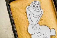 Nahaufnahme des präzisen Schnitts, der die Konturen des Olaf Kuchens auf dem Backblech definiert.