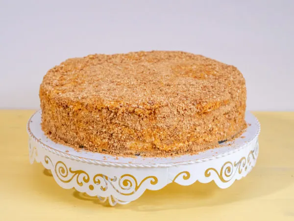 Nahaufnahme einer angeschnittenen russischen Honigtorte (Medovik) mit sichtbaren Schichten und Sauerrahmcreme, ideal als Geburtstagstorte.