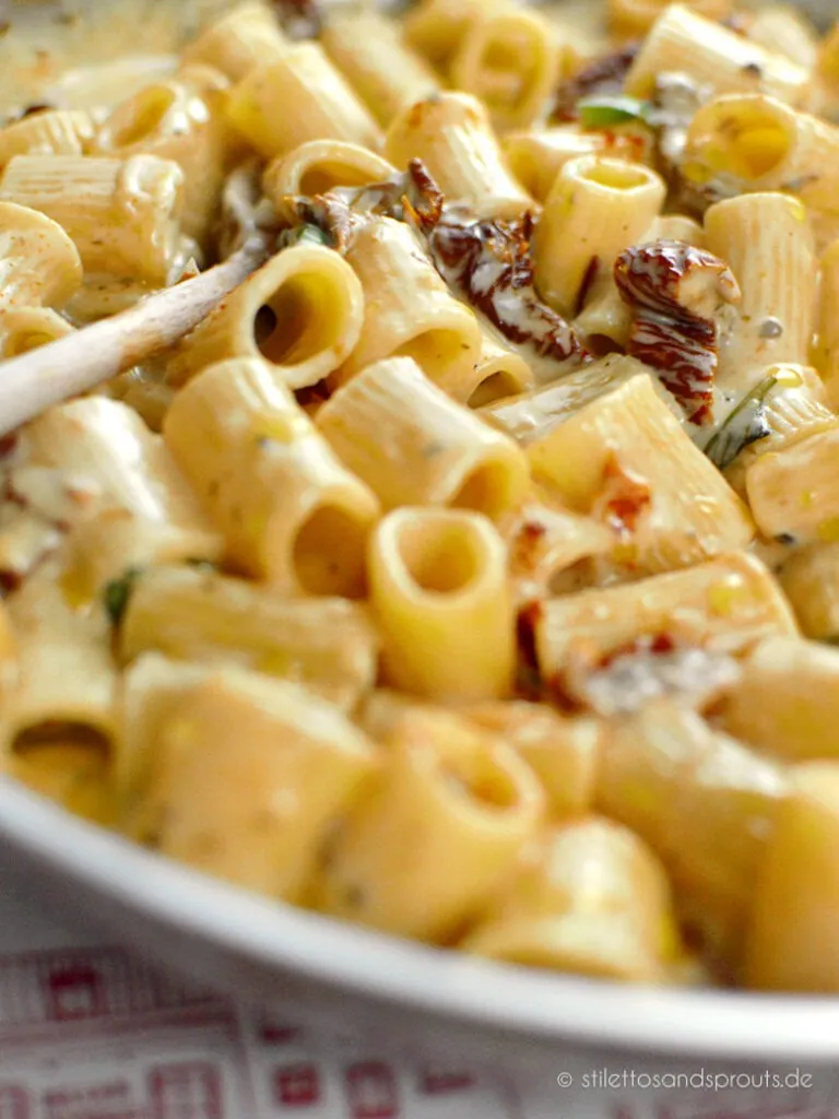 Nahaufnahme einer cremigen italienischen Pasta mit sonnengetrockneten Tomaten, Parmesan und Kräutern, ein wahrer Genuss