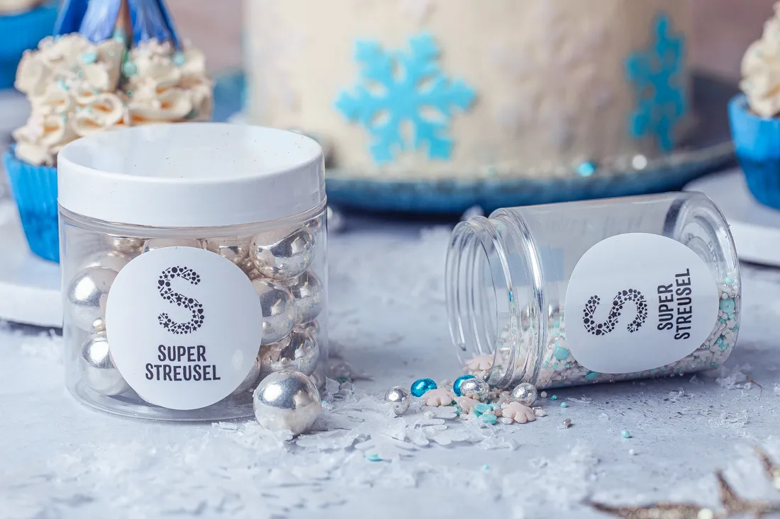 Nahaufnahme einer Frozen Torte, verziert mit blauen und weißen Streuseln sowie essbaren Schneeflocken