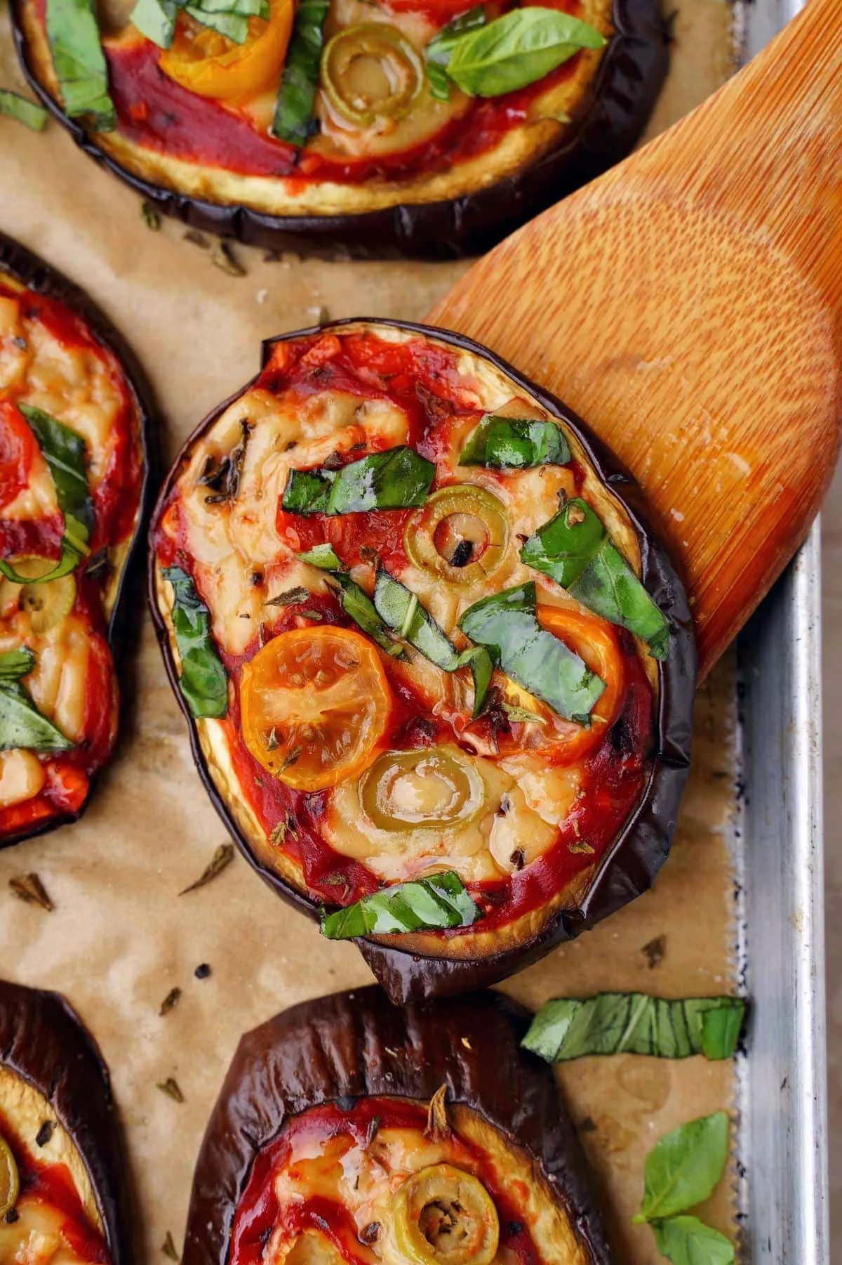 Nahaufnahme einer Scheibe veganer Auberginen-Pizza auf einem Holzspatel, gluten- und getreidefrei, eine leckere leichte Mahlzeit.