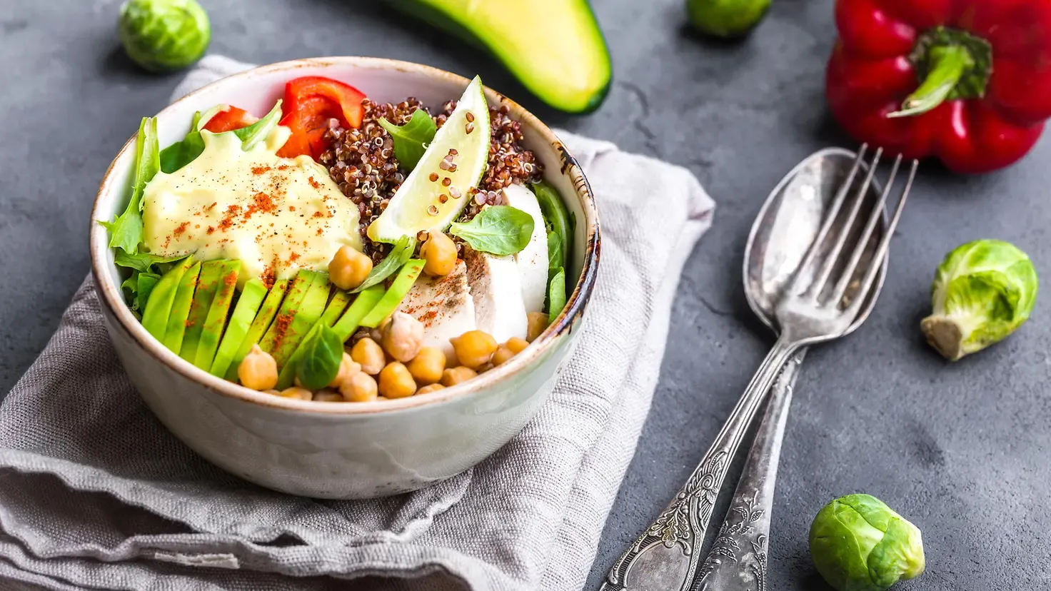 Nahaufnahme einer Schüssel mit Rührei, Avocado, Beeren und Nüssen, die eine gesunde Low-Carb-Mahlzeit darstellt.