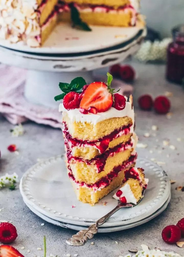 Nahaufnahme einer sommerlichen veganen Himbeer-Sahnetorte mit leuchtenden Erdbeeren.
