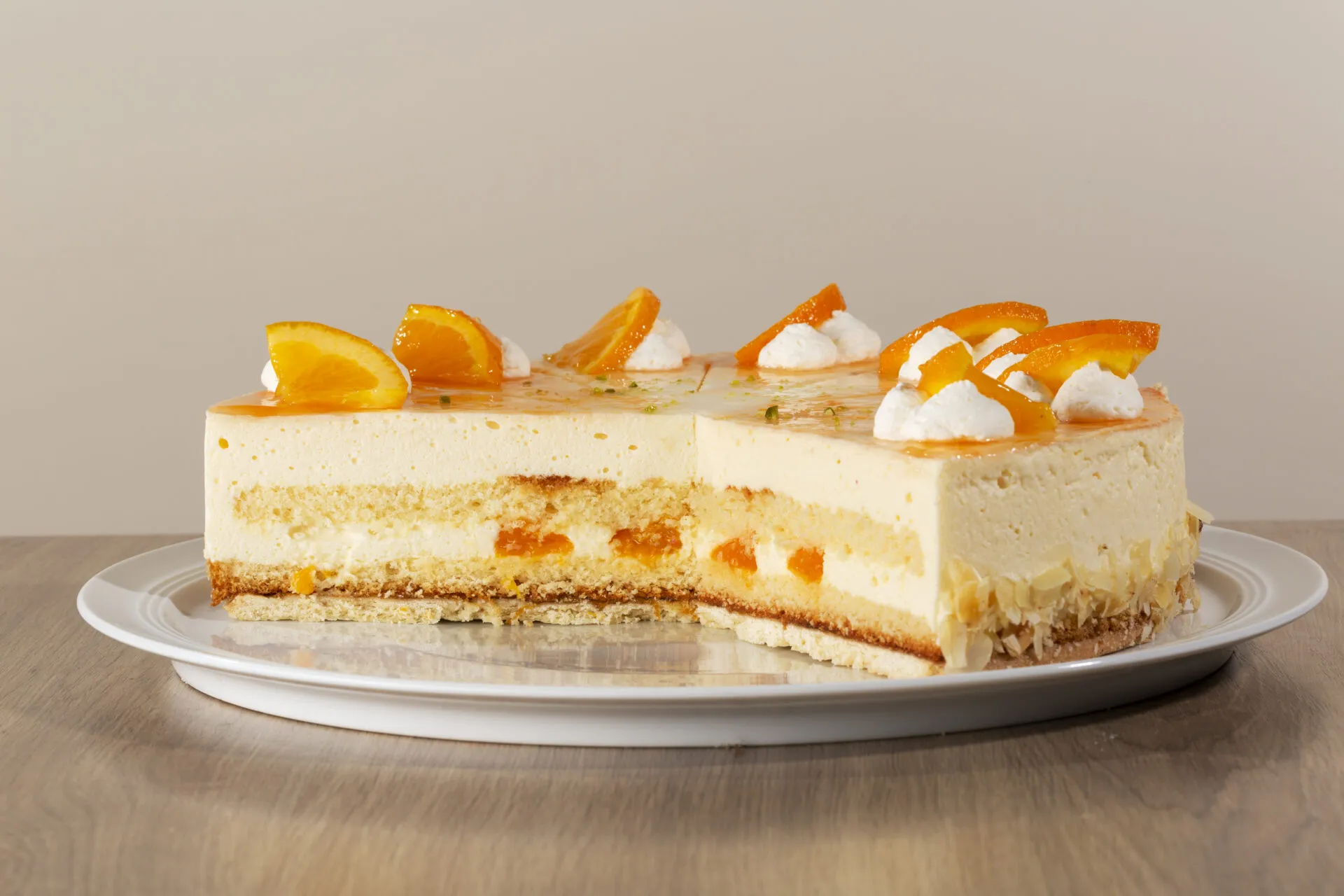 Nahaufnahme einer sorgfältig dekorierten Orangen-Käsesahne Torte mit Mandarinen und gehackten Mandeln, perfekt für festliche Anlässe