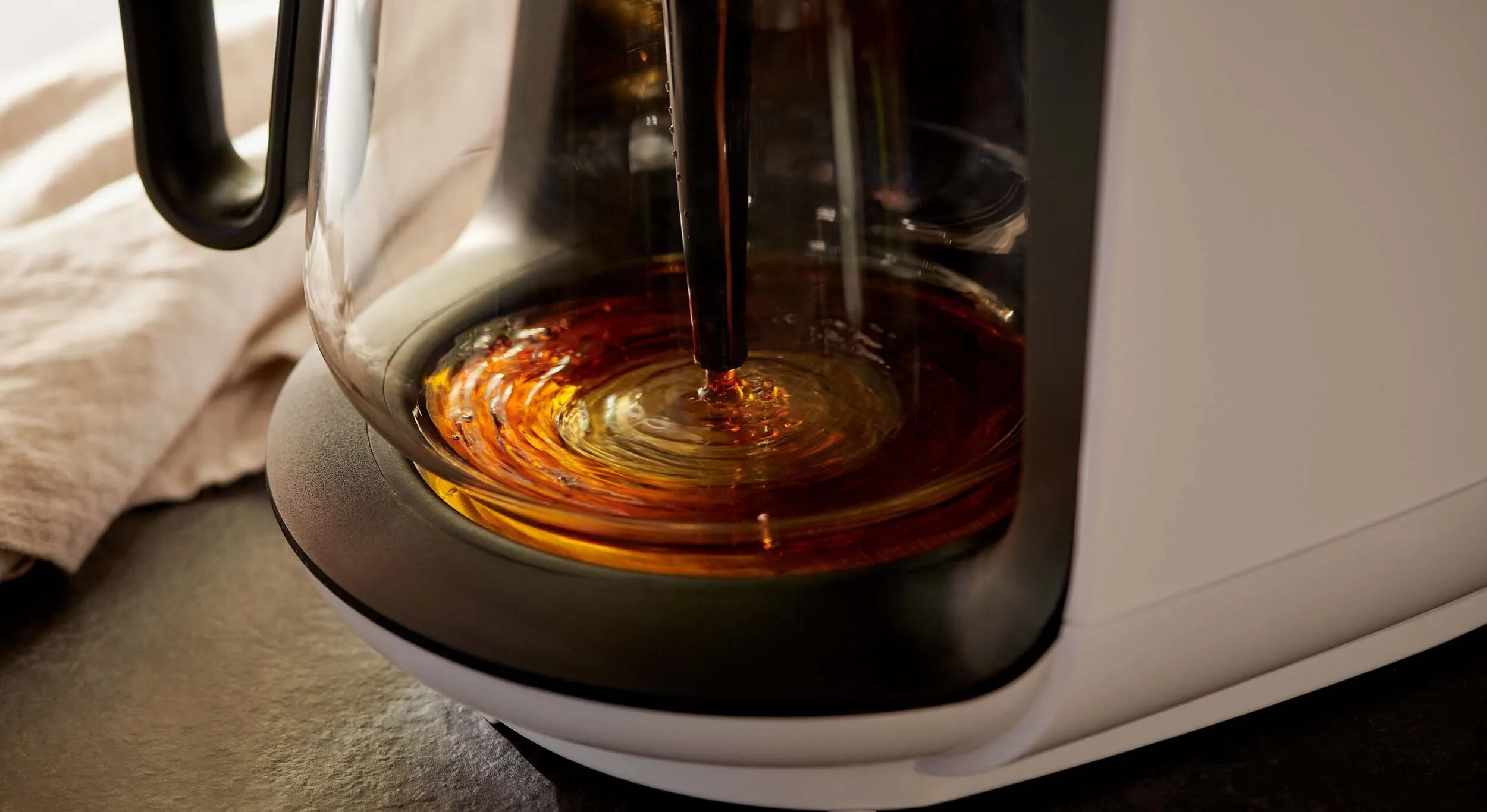 Nahaufnahme einer Tchibo Let's Brew Filterkaffeemaschine mit Glaskanne auf einer Küchenzeile, bereit für die Entkalkung.