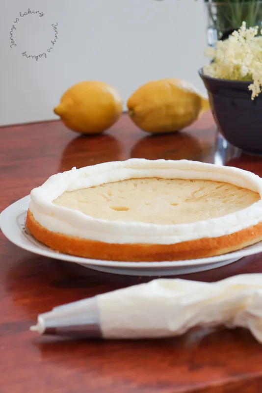 Nahaufnahme einer Torte, bei der ein Creme-Rand mit Spritzbeutel aufgetragen wird, um die Füllung zu halten.