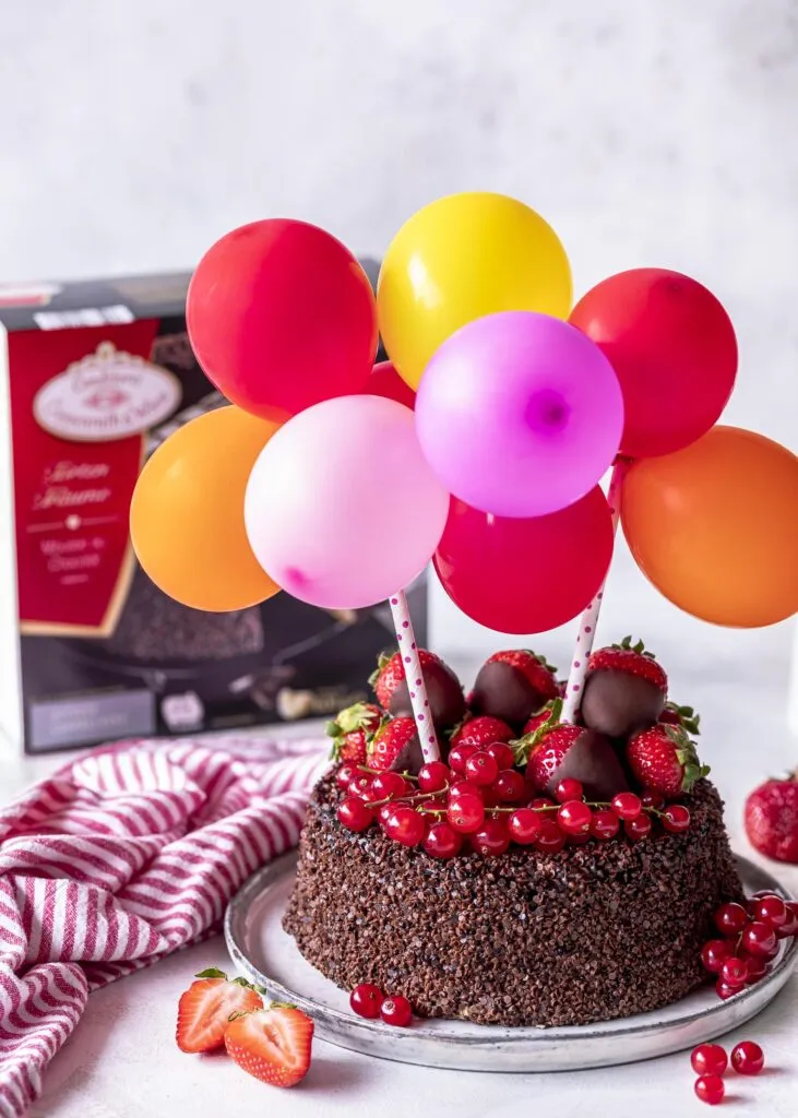 Nahaufnahme einer Torte mit einer DIY-Luftballon-Girlande und Schokoladen-Topper
