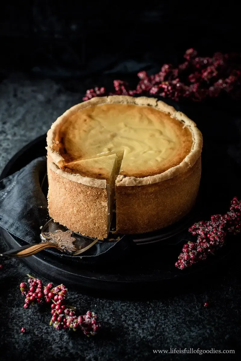 Nahaufnahme eines angeschnittenen, cremigen Käsekuchens auf einem Teller, perfekt gebacken