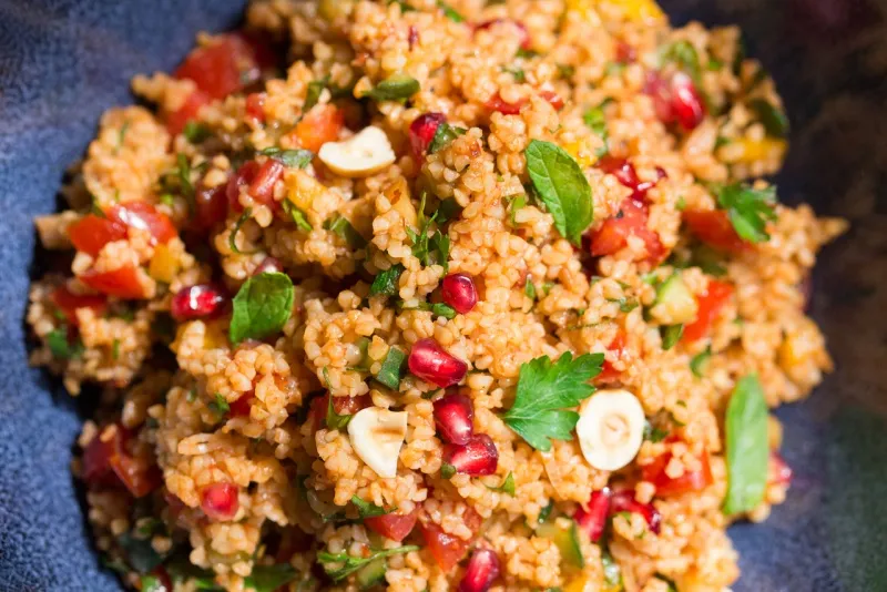 Nahaufnahme eines farbenfrohen Kisir-Salats mit frischen Kräutern und Granatapfelkernen