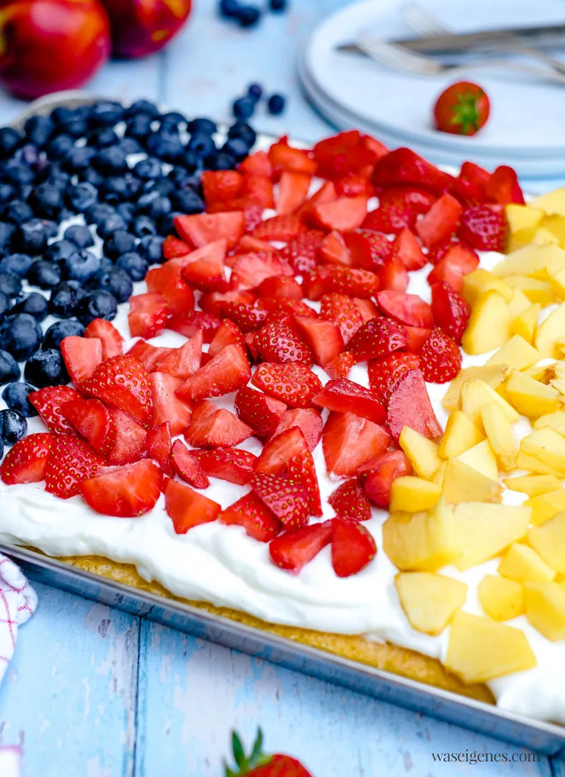 Nahaufnahme eines köstlichen Fanta-Blechkuchens mit cremiger Schmand-Sahne und leuchtendem Obstbelag