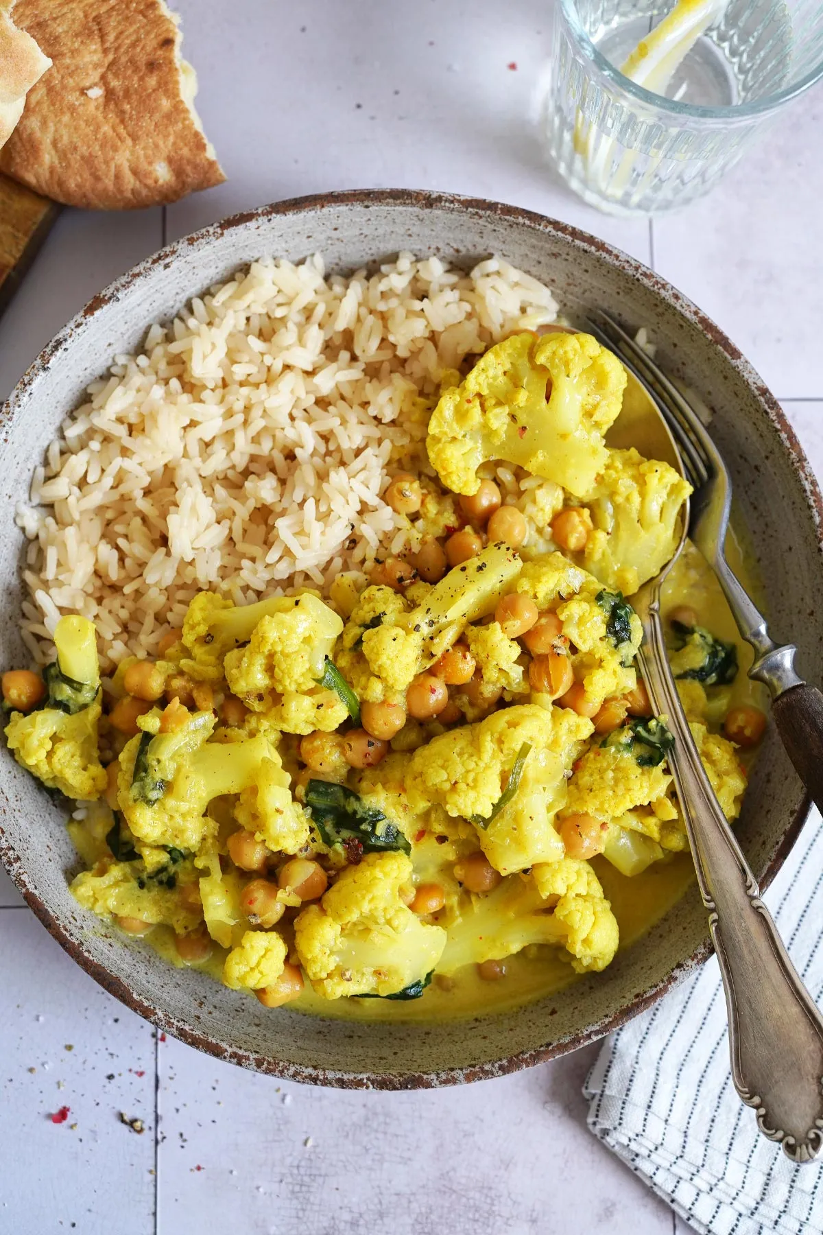 Nahaufnahme eines köstlichen veganen Blumenkohl-Kichererbsen-Currys mit Kräutern und Reis
