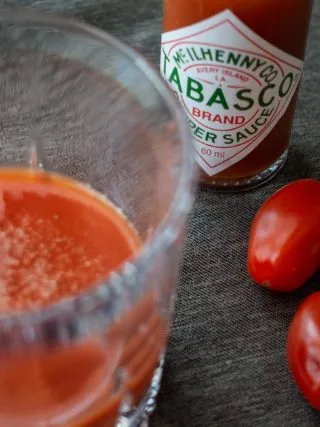 Nahaufnahme eines roten Mexikaner Getränks im Shotglas, umgeben von Gewürzen