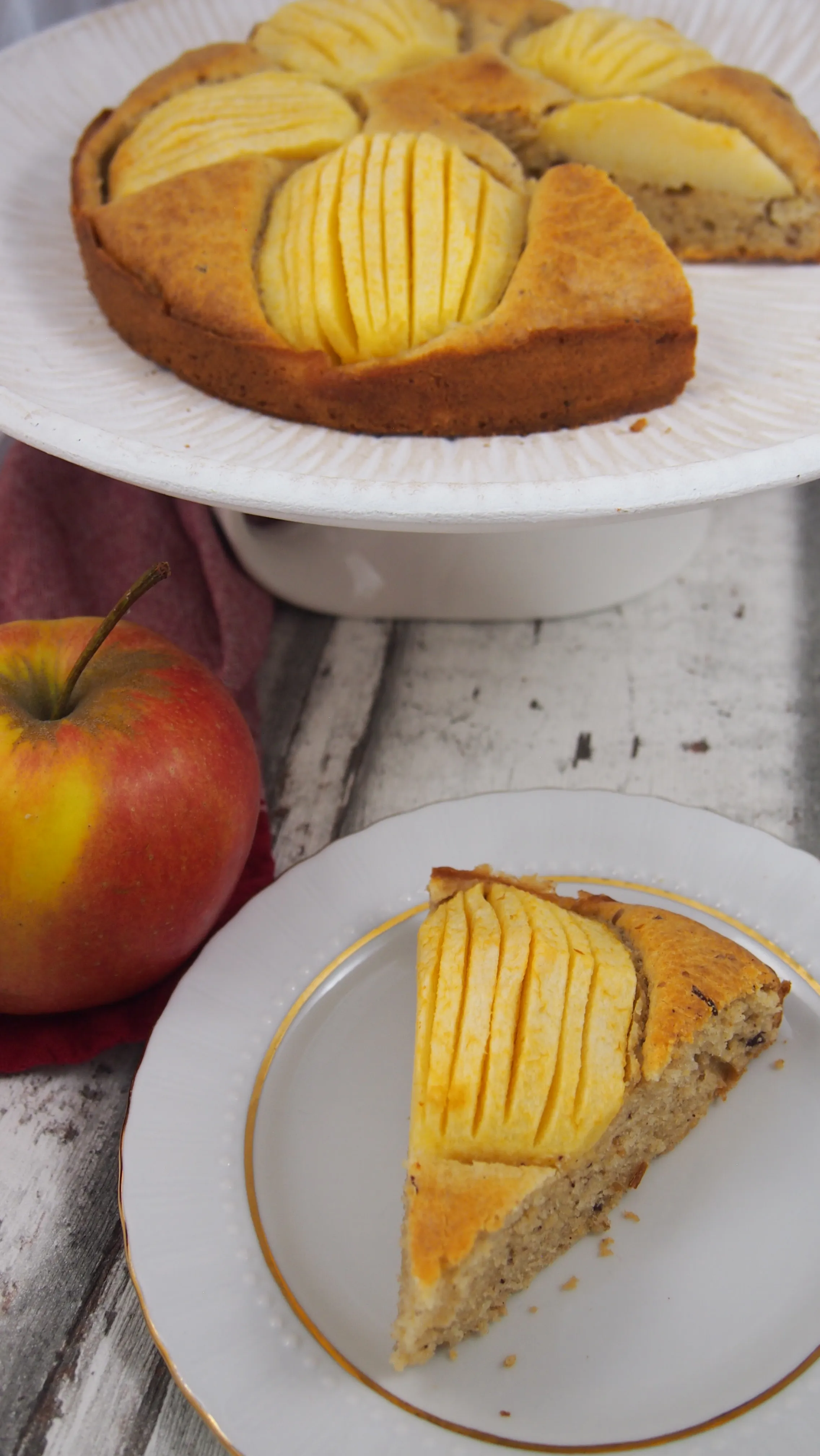 Nahaufnahme eines saftigen Apfelkuchens ohne raffinierten Zucker, die gleichmäßig verteilten Apfelstücke sind leicht in den Teig eingedrückt.