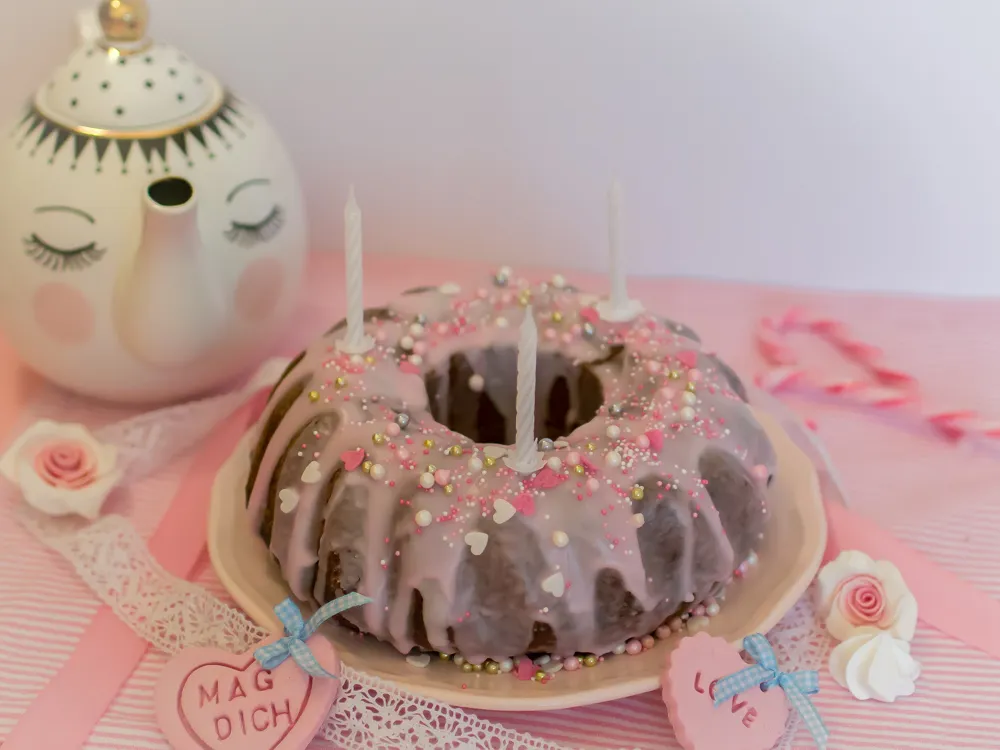 Nahaufnahme eines saftigen Zitronenkuchens mit rosa Zuckerguss und bunten Streuseln
