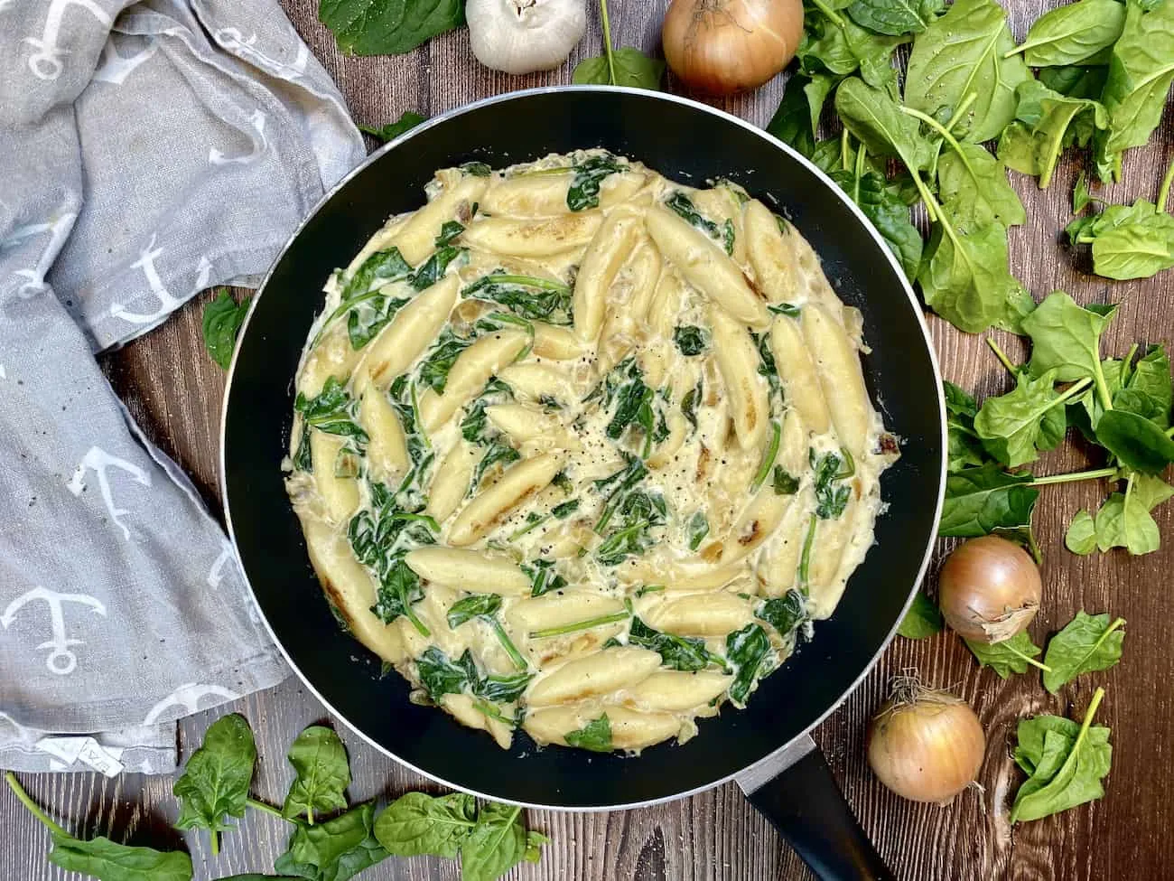 Nahaufnahme von cremigen Schupfnudeln mit Blattspinat in einer Schale, angerichtet und bereit zum Genießen