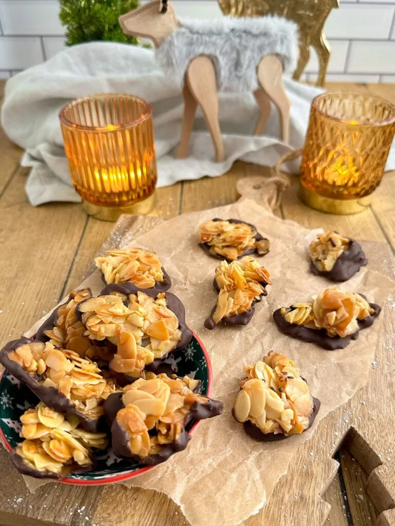 Nahaufnahme von frisch gebackenen, karamellisierten Florentiner Plätzchen mit gebräunten Mandeln, bereit zum Bestreichen mit Schokolade.