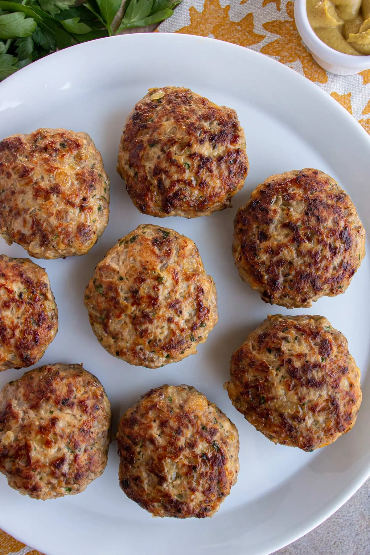 Nahaufnahme von frisch gebratenen deutschen Buletten auf einem weißen Teller, serviert mit einem Klecks Senf.