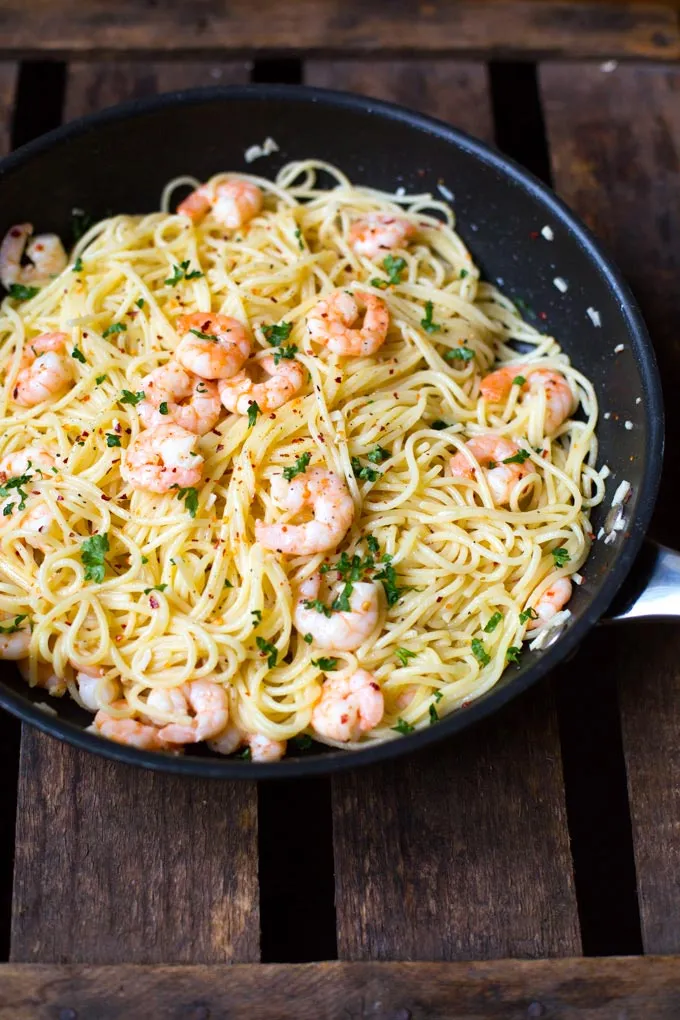 Nahaufnahme von frisch gekochter Scampi Pasta mit reichlich Sauce, Zitronenscheiben und Kräutern in einer Pfanne, bereit zum Servieren.