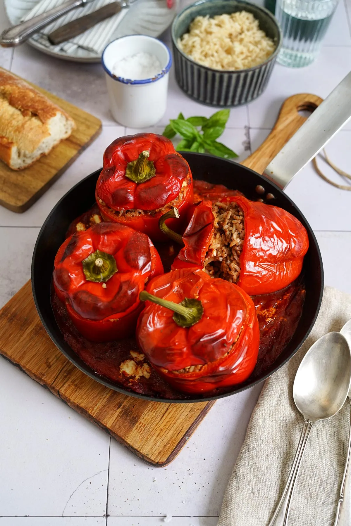 Nahaufnahme von gefüllten Paprika mit Reis, die mit Feta bestreut und in Tomatensoße gebettet sind