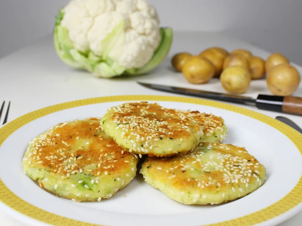 Nahaufnahme von goldbraunen, vielseitigen Karfiol-Laibchen mit Kartoffeln und Lauch, ideal für einfache Blumenkohlrezepte