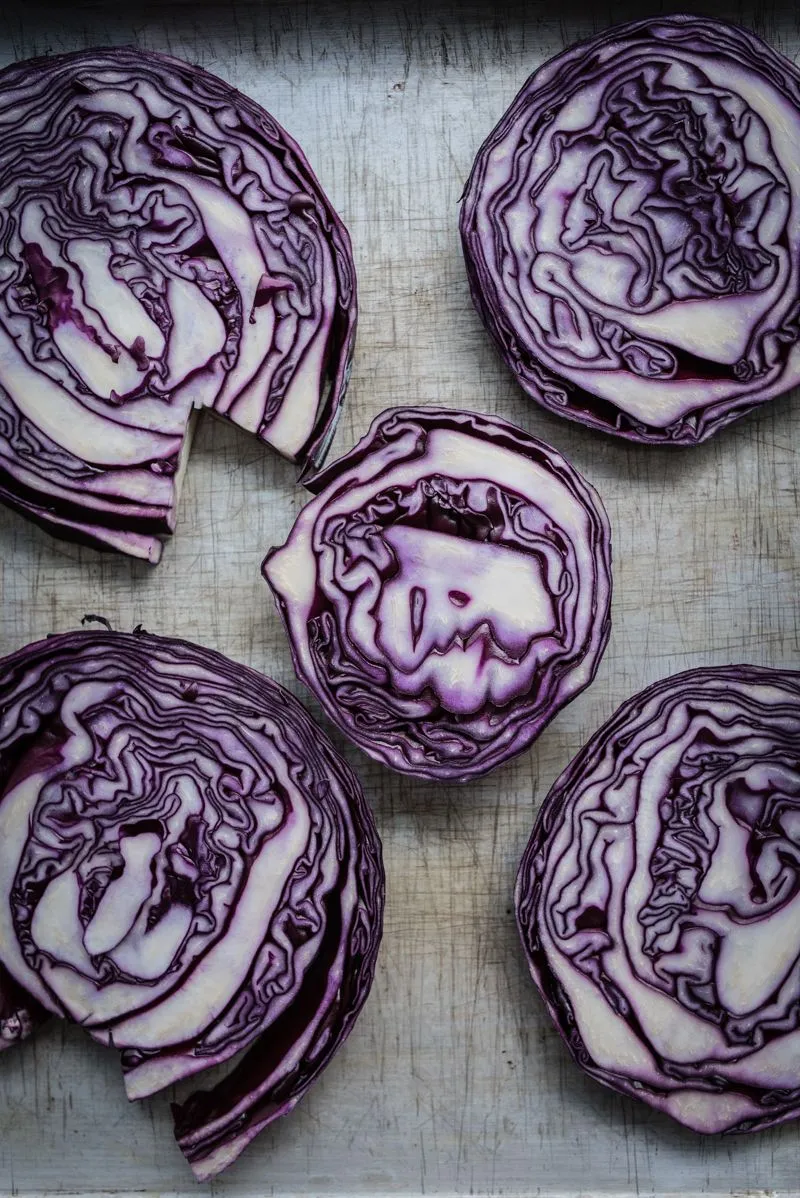 Nahaufnahme von karamellisiertem Rotkohl vom Blech mit Wurststücken und Äpfeln