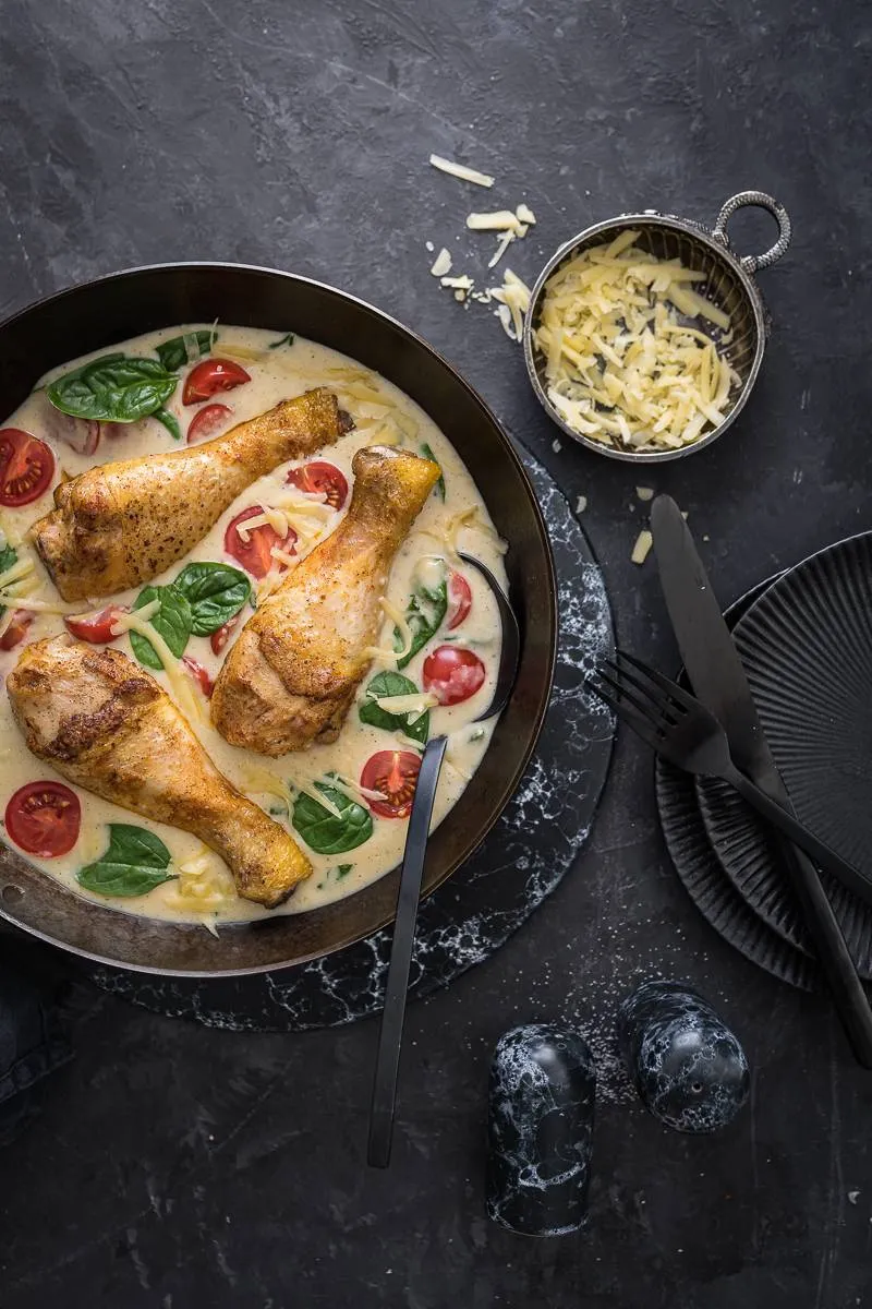 Nahaufnahme von Maispoulardenpfanne mit Spinat und Tomaten, ein vielseitiges Festtagsgericht